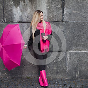 Beautiful young and happy blond woman with colorful umbrella on the street. The concept of positivity and optimism