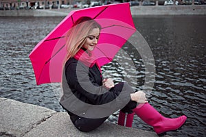 Beautiful young and happy blond woman with colorful umbrella on the street. The concept of positivity and optimism
