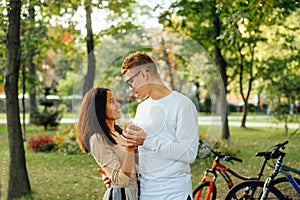 Beautiful young happy couple hugging in autumn park, looking at each other and smiling. Portrait of a smiling beautiful couple