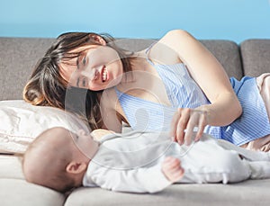 Beautiful young happy woman with her newborn baby lies on the co