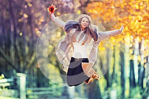 Beautiful young happy woman jumping in autumn park