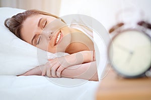 Beautiful young and happy woman sleeping while lying in bed comfortably and blissfully smiling