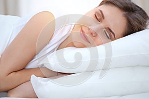 Beautiful young and happy woman sleeping while lying in bed comfortably and blissfully smiling