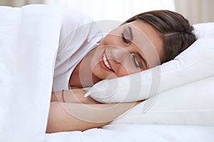 Beautiful young and happy woman sleeping while lying in bed comfortably and blissfully smiling