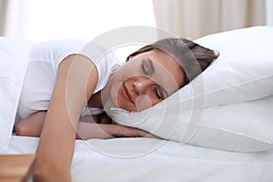 Beautiful young and happy woman sleeping while lying in bed comfortably and blissfully smiling