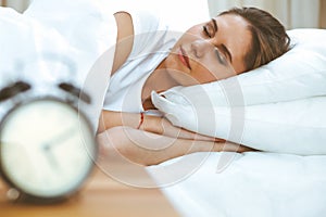 Beautiful young and happy woman sleeping while lying in bed comfortably and blissfully smiling