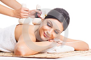 Beautiful, young and healthy woman on bamboo mat in spa salon is having massage.