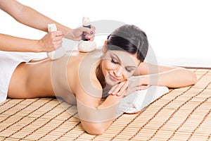 Beautiful, young and healthy woman on bamboo mat in spa salon is having massage.