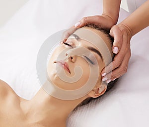 Beautiful, young and healthy woman having face massage in spa salon. Hands of professinal masseur. Spa, health and