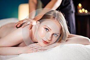 Beautiful, young and healthy woman is having hot stone massage. Spa Treatment