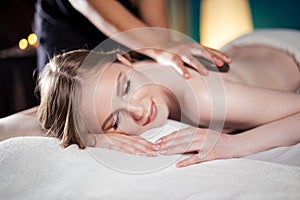 Beautiful, young and healthy woman is having hot stone massage. Spa Treatment