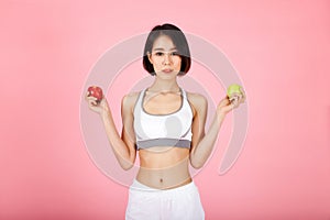 Beautiful young healthy woman with red apple and green apple isolated over pink background. Diet and healthy eating