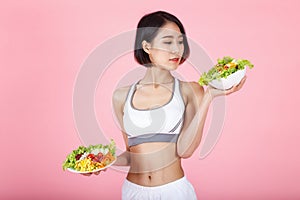 Beautiful young healthy woman with salad bowl isolated over pink background. Fitness Diet and healthy eating concept