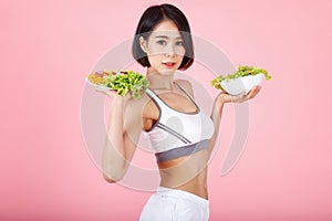 Beautiful young healthy woman with salad bowl isolated over pink background. Fitness Diet and healthy eating concept