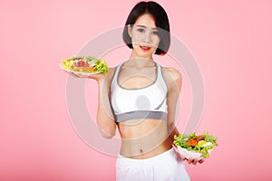 Beautiful young healthy woman with salad bowl isolated over pink background. Fitness Diet and healthy eating concept