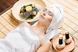 Beautiful, young and healthy woman in spa salon on bamboo mat. S