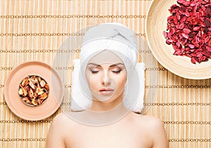 Beautiful, young and healthy woman in spa salon on bamboo mat. S