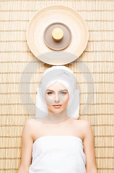 Beautiful, young and healthy woman in spa salon on bamboo mat. S
