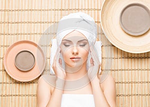 Beautiful, young and healthy woman in spa salon on bamboo mat. S