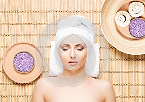 Beautiful, young and healthy woman in spa salon on bamboo mat. S