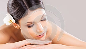 Beautiful, young and healthy woman in spa salon. Massage treatment over grey background. Spa, health and healing.