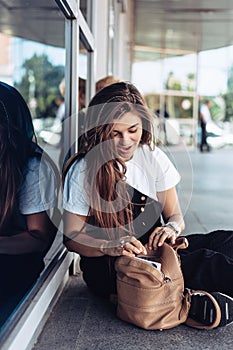 Beautiful young hipster girl is looking for something in her bag