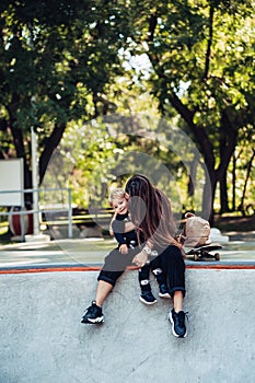 Beautiful young hipster mom and little son at the skatepark