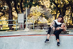 Beautiful young hipster mom and little son at the skatepark