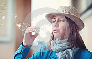 Beautiful young hipster woman in hat blowing bubbles