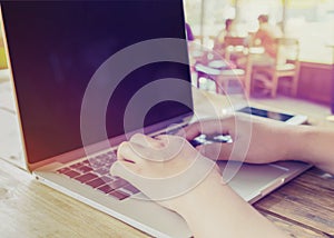 beautiful young hipster woman`s hands busy working on her laptop sitting at wooden table in a coffee shop