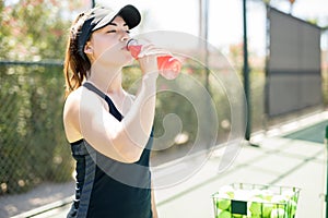 Beautiful tennis player drinking energy drink