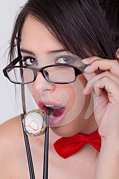 Beautiful young hispanic woman eating sushi roll