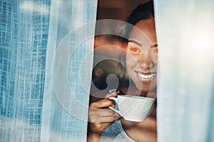 A beautiful young Hispanic woman enjoying a warm cup of coffee for breakfast. One mixed race female drinking tea while