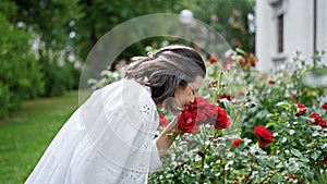 Beautiful young hispanic woman smelling red roses at the park