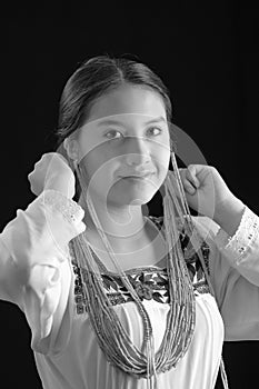 Beautiful young hispanic woman wearing light colored blouse with traditional embroided edges, attaching typical