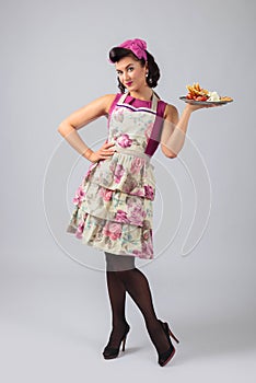 Beautiful young housewife in purple dress and apron with dessert photo