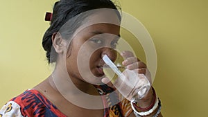 Beautiful young Indian woman drinking a fresh glass of water and showing thumbs up at home.