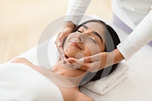 Beautiful young indian woman enjoying face lifting massage in spa