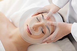 Beautiful young indian woman receiving acupressure head massage in spa salon