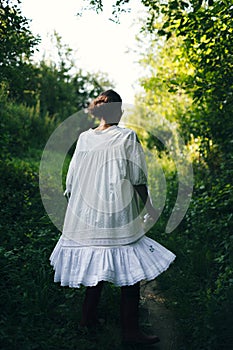 Beautiful young Indian woman smelling flower in the park, wearing white dress