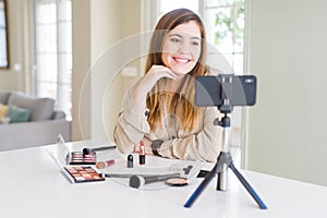 Beautiful young influencer woman recording make up video tutorial looking away to side with smile on face, natural expression