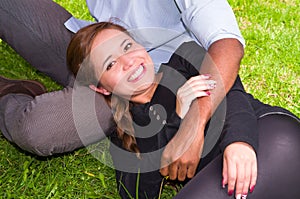 Beautiful young interracial couple in sitting garden environment, embracing and smiling happily to camera