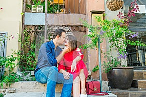 Beautiful young kissing couple sitting on the stairs on mediterranean city street. Love, dating, romance, joy and happiness. Lifes