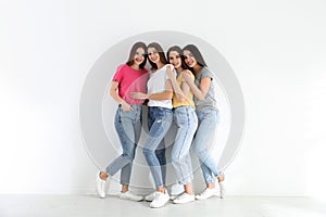 Beautiful young ladies in jeans and colorful t-shirts near white wall. Woman`s Day