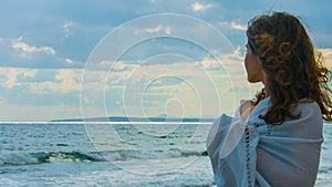 Beautiful young lady on beach looking at horizon, thinking of love, romance