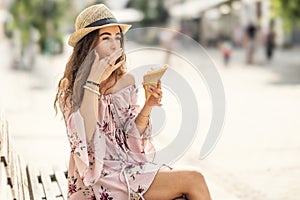 A beautiful young lady is licking her fingers from melted ice cream on a hot summer day