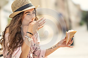 A beautiful young lady is licking her fingers from melted ice cream on a hot summer day