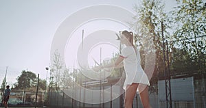 Beautiful young lady with long sportiv legs playing tennis on the tennis court outside on sunny day.
