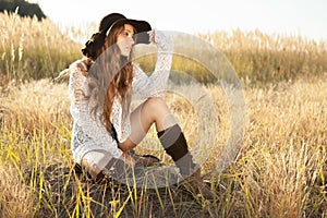 Beautiful young lady model sitting in field at sunrise