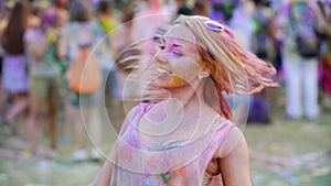 Beautiful young lady moving body to music at color festival, vertical pan